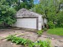 Detached garage with a weathered white door and overgrown surroundings at 2606 Raible Ave, Anderson, IN 46011