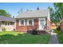 Charming brick home featuring a gray roof, white shutters, and green front lawn at 5232 E 10Th St, Indianapolis, IN 46219