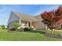 Well-maintained home showcasing brick siding, a covered porch, and lush landscaping with mature trees at 5560 Goodwin St, Indianapolis, IN 46234