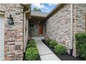 Brick pathway leading to a red front door surrounded by green shrubbery at 7329 Pymbroke Dr, Fishers, IN 46038