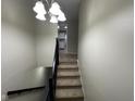 Carpeted stairs with a dark railing lead to the upper level with a decorative light fixture at 7514 Ruskin Pl, Indianapolis, IN 46226