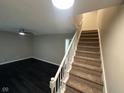 View of living room, and staircase with carpet runner and white banister and dark flooring in the living area at 8030 Winchester Pl, Indianapolis, IN 46227
