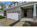 Inviting townhome entrance with a brick facade, two-car garage, and covered porch with a decorative wreath at 8266 Glacier Ridge Dr, Fishers, IN 46038