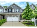 Charming townhome featuring a two-car garage, gray siding, and lush landscaping in a suburban setting at 8266 Glacier Ridge Dr, Fishers, IN 46038