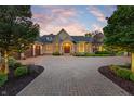 Striking home with brick driveway, manicured landscaping, and warm exterior lighting at dusk at 860 Chatham Hills Blvd, Westfield, IN 46074