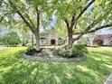 Charming brick home boasts a meticulously landscaped front yard, complete with mature trees and lush green grass at 897 Copperwood Dr, Carmel, IN 46033