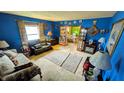 Cozy living room featuring bright blue walls, plush sofas, and abundant natural light from a window at 100 N 6Th Ave, Beech Grove, IN 46107