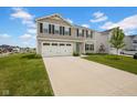 Two-story home featuring a two-car garage, tan siding, black shutters and a well-maintained green lawn with a long driveway at 13887 N Hawkers Hill Dr, Camby, IN 46113