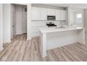 Bright kitchen featuring an island, wood grain flooring, stainless steel appliances, and white cabinets at 18967 Seaforth Way, Westfield, IN 46074