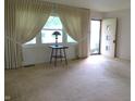 Bright living room with large window, neutral carpet, and an open entry door, enhancing the home's inviting atmosphere at 2110 Fisher Ave, Speedway, IN 46224