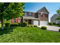 Beautiful two-story home with brick and siding, red shutters, a well-manicured lawn and a two car garage at 2209 S Logan Dr, New Palestine, IN 46163