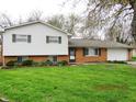 Traditional home featuring brick and white siding, complemented by green shutters and a lush green lawn at 2414 Constellation Dr, Indianapolis, IN 46229