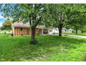 View of a well-kept ranch-style home with mature landscaping and a swing hanging from a tree in the front yard at 356 Daugherty St, Columbus, IN 47201