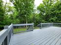 Large backyard deck with grey wood and railing with a green view of the backyard forest at 6538 N Tutterow Rd, Monrovia, IN 46157