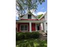 Charming red two-story home featuring a covered front porch with white columns and manicured landscaping at 1156 Spruce St, Indianapolis, IN 46203