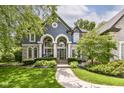 Charming blue home showcasing arched windows, white pillars, and professional landscaping in the front yard at 13017 Water Ridge Dr, McCordsville, IN 46055