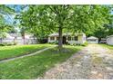 Attractive home with a well-maintained lawn, mature trees, and a gravel driveway at 332 Campus Ln, Indianapolis, IN 46219