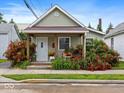 Charming home featuring a covered front porch surrounded by vibrant landscaping and red roses at 334 E Pennsylvania St, Shelbyville, IN 46176