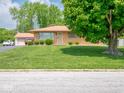 Beautiful brick home featuring a lush green lawn, mature trees, and well-maintained landscaping at 3538 Whalen Ave, Indianapolis, IN 46227