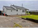 Quaint single-story home with a well-maintained lawn, driveway and neutral-colored siding under an overcast sky at 613 Anderson Rd, Anderson, IN 46017