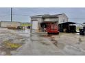 View of the detached garage of this property, including work equipment and a spacious lot in rainy conditions at 613 Anderson Rd, Anderson, IN 46017
