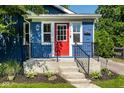 Blue home featuring a vibrant red front door, black railing and well-maintained landscaping at 6264 Central Ave, Indianapolis, IN 46220