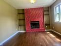 Spacious room with hardwood floors, a red brick fireplace, and built-in shelving at 7824 Hearthstone Way, Indianapolis, IN 46227
