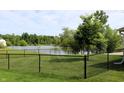 Large backyard with a black chain-link fence offers views of a peaceful lake at 994 Young'S Creek Dr, Franklin, IN 46131