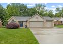 Charming brick home boasts a well-manicured lawn and attached three car garage at 1124 Enchanted View Dr, Mooresville, IN 46158