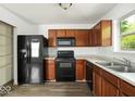 Functional kitchen featuring wood cabinetry, a complete black appliance set, and durable laminate flooring at 11821 Wapiti Way, Noblesville, IN 46060