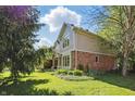 Lush green backyard view of tan colored home with brick accents and manicured landscaping at 12335 Old Stone Dr, Indianapolis, IN 46236