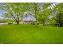 Expansive backyard featuring lush green grass and mature trees providing ample shade at 2900 Helms Rd, Anderson, IN 46016