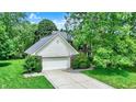 An aerial view of a beautiful home featuring a two-car garage, long driveway, and a yard full of mature trees at 50 Charing Cross Rd, Indianapolis, IN 46217