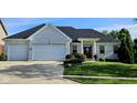 A well-kept white brick home features a two car garage, well manicured landscaping, and a large driveway at 5347 Sampson Dr, Indianapolis, IN 46237