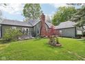Charming backyard features a well-maintained lawn, a brick chimney, and a small deck at 6210 Mckinley Ct, Indianapolis, IN 46220