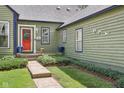 Exterior view of a home with green siding, a bright red front door, and lovely landscaping at 6210 Mckinley Ct, Indianapolis, IN 46220