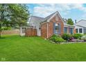Back view of brick home with a well-manicured lawn and partial fence at 6789 Passage Cir, Indianapolis, IN 46250