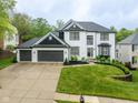 Beautiful two-story white home featuring a three-car garage, manicured lawn, and elegant landscaping at 7022 Tamarind Ct, Indianapolis, IN 46236