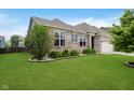 Landscaped front yard showcasing lush green grass, flowering bushes, and a brick home at 7724 Dunleer Dr, Brownsburg, IN 46112