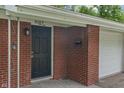 Close up image showing the address of a brick home, front door, and a white garage at 8109 E Penway St, Indianapolis, IN 46226