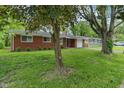 Picture of a single story brick house with a black roof, a garage, and a tree at 8109 E Penway St, Indianapolis, IN 46226