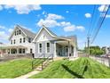 Charming home with manicured lawn, light blue siding, and a covered front porch with blue chairs at 1015 N Beville Ave, Indianapolis, IN 46201