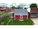 Quaint red home with a gray roof and white trim, set against a backdrop of lush greenery at 104 W Pearl St, Trafalgar, IN 46181