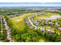 Aerial view showcasing a residential community nestled around a golf course and serene pond at 10505 Golden Bear Way, Noblesville, IN 46060