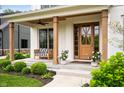 Inviting front porch with wooden columns, a cozy bench swing, and a stylish wooden door at 10505 Golden Bear Way, Noblesville, IN 46060