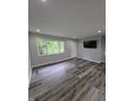 Bright living room with new gray floors, a large window, and a mounted television at 1205 Meadow Ln, Lebanon, IN 46052