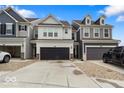 Exterior showcasing a row of townhomes with black garage doors and neutral color schemes under a blue sky at 14350 Ludwell Ct, Fishers, IN 46037
