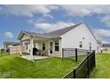 Back exterior view showcasing a covered patio perfect for outdoor enjoyment and a black-fenced yard at 200 Mission Terrace Dr, Whiteland, IN 46184