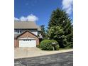 Exterior view showcasing the home's brick and siding details, mature trees, and driveway at 213 Golf Ct, Greenwood, IN 46143