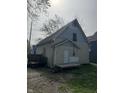 Rear exterior view of a weathered two-story home with a small porch and overgrown yard at 330 N Lasalle St, Indianapolis, IN 46201